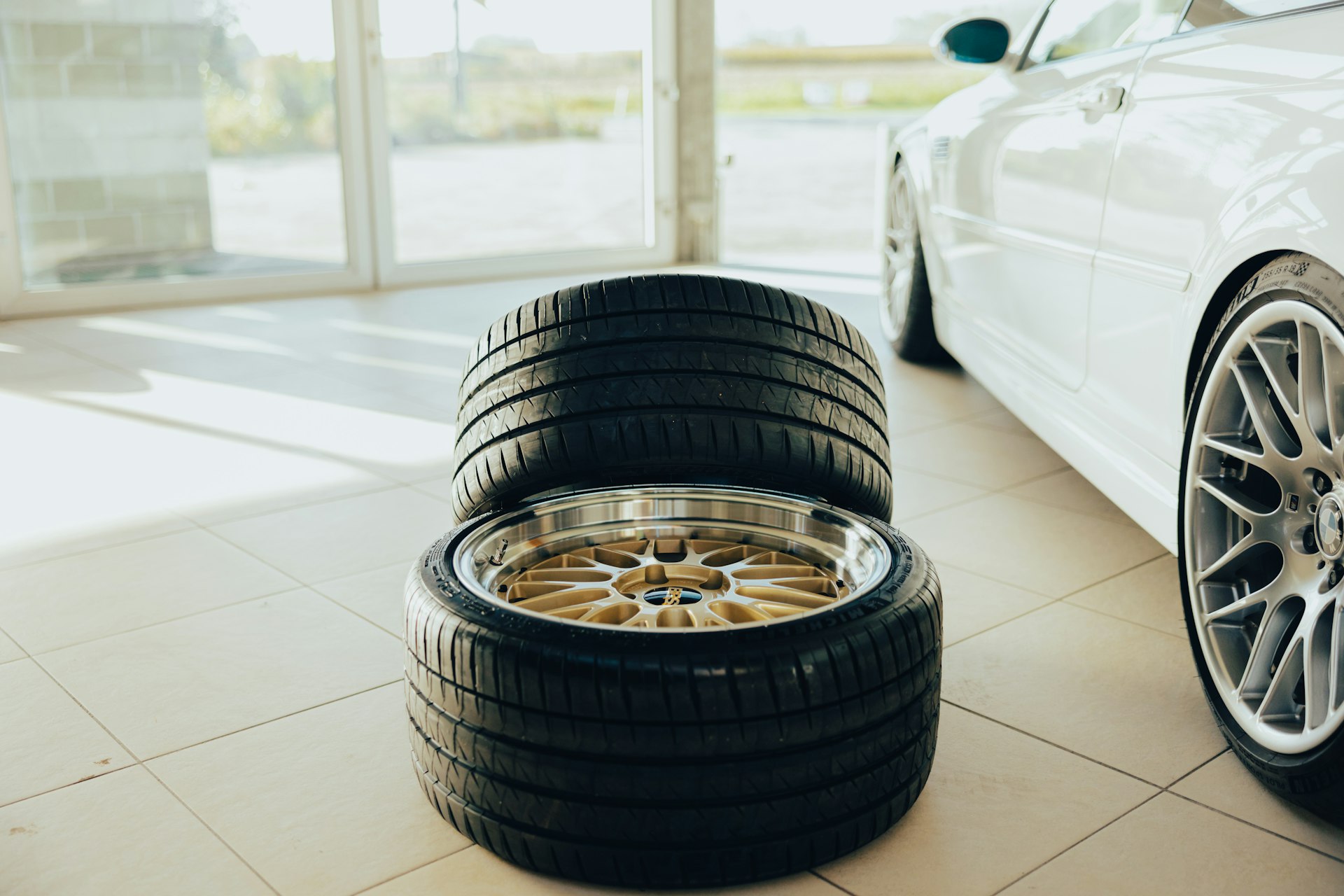 a white car parked in a garage next to two tires